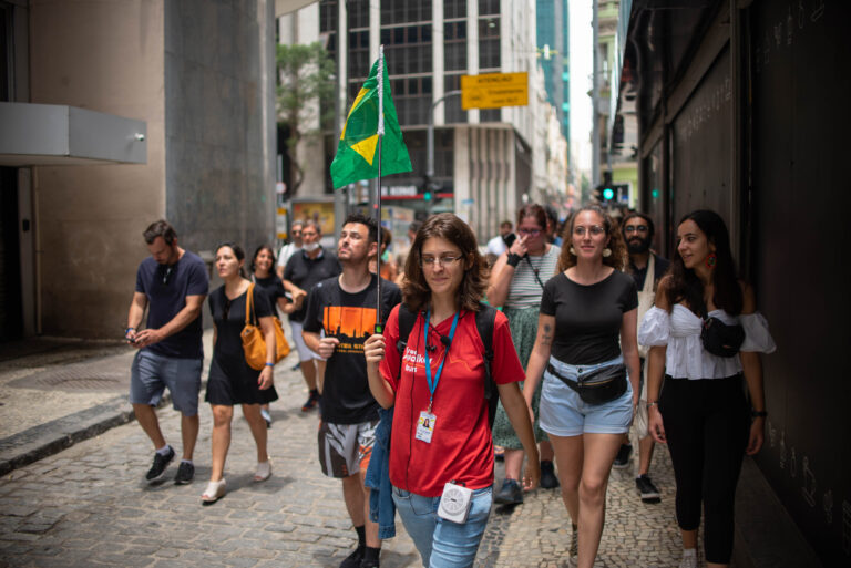 Guide walking with the Brazilian flag up while the group follows