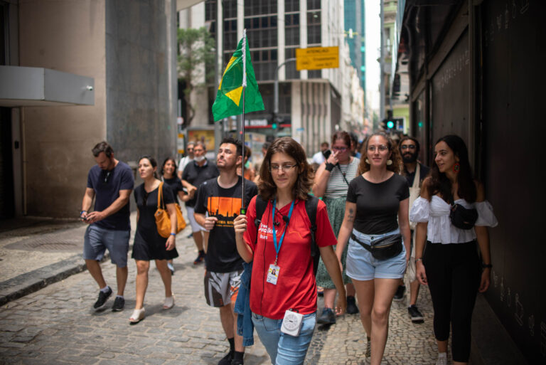 Guia caminhando com a bandeira do Brasil enquanto o grupo acompanha